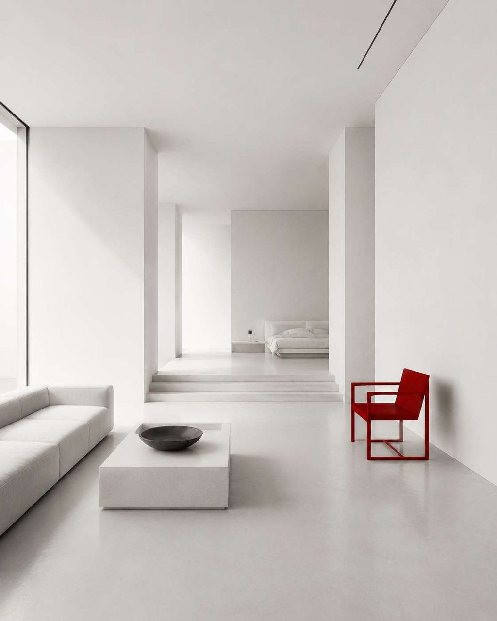 A minimal white living space where a single red chair is the only saturated colour.
